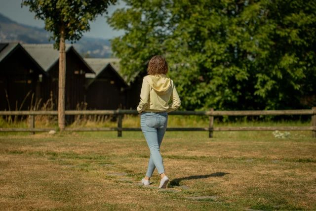 Frau geht über eine Wiese, von hinten fotografiert